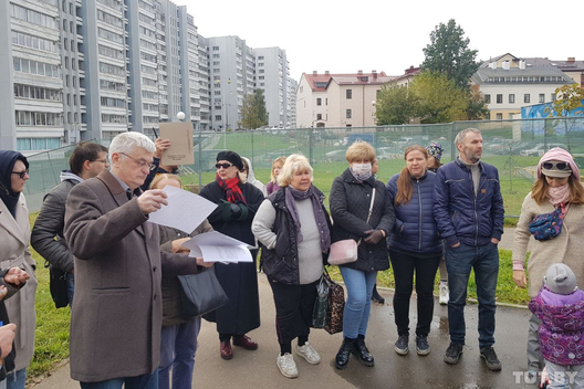 Мясцовыя жыхары на сходзе збіраюць подпісы пад калектыўным зваротам. За іх спіной — абгароджаная дзіцячая пляцоўка Мясцовыя жыхары на сходзе збіраюць подпісы пад калектыўным зваротам. За іх спіной — абгароджаная дзіцячая пляцоўка