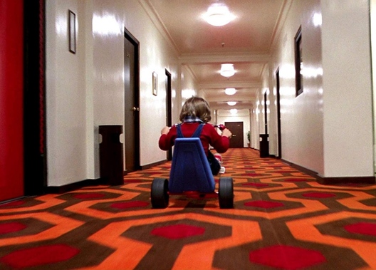 Персанаж Дэні Торанс едзе на ровары па каляровым дыване Персанаж Дэні Торанс едзе на ровары па каляровым дыване